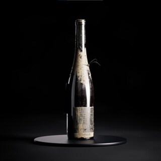Eine Weinflasche aus der Schlammflut in Ahrtal steht auf einem schwarzen Ständer (Foto: DASDING, Screenshot: https://www.niftee.eu/de/title/FLUTWEIN-14)