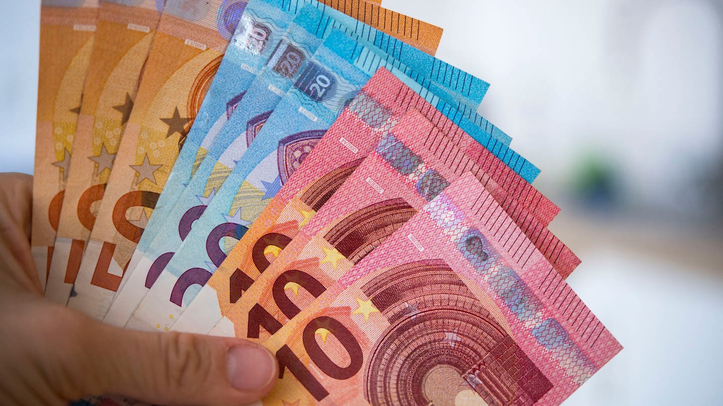 Eine Frau hält Banknoten von 10, 20 und 50 Euro gefächert in der Hand.