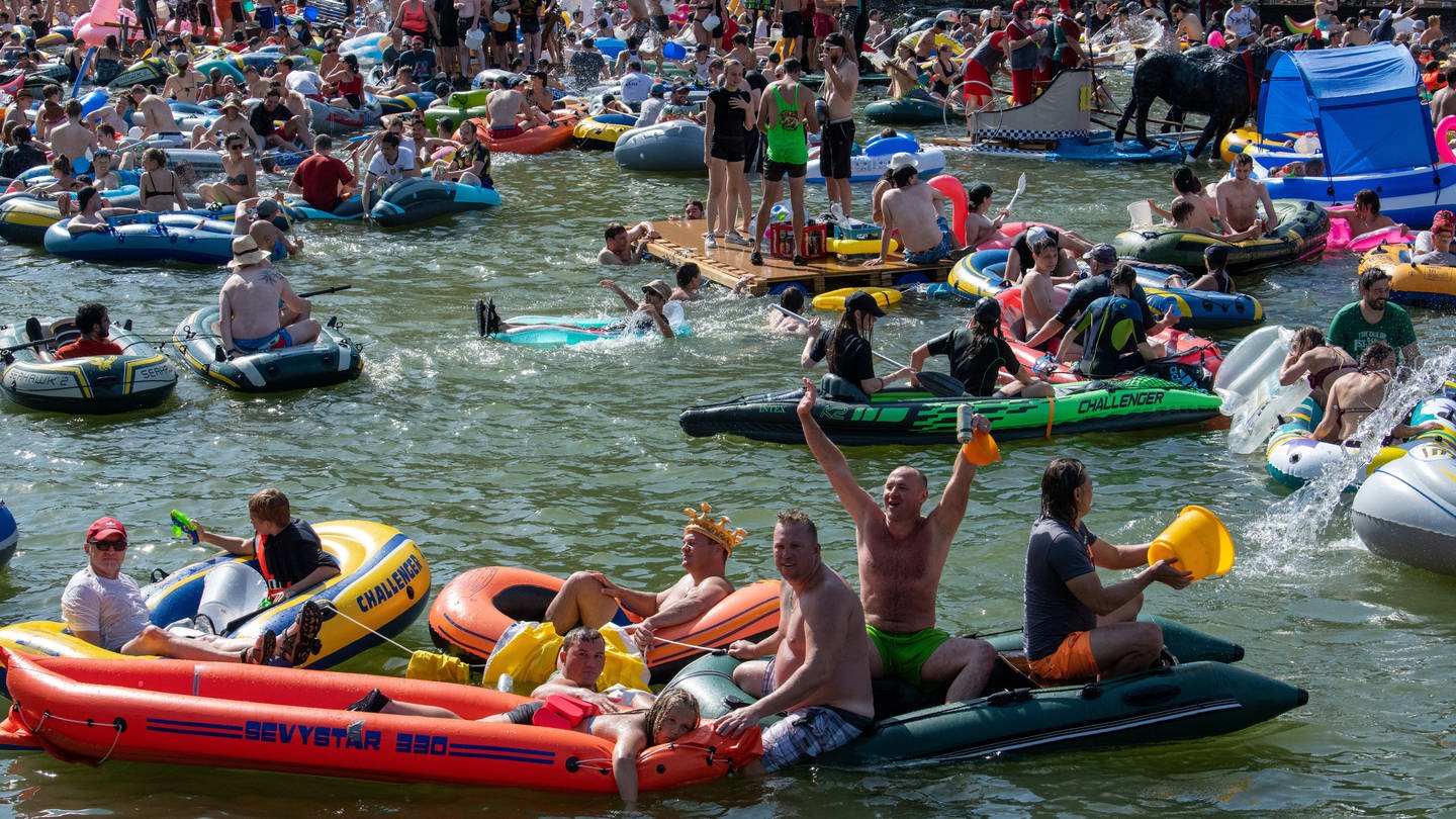 Zahlreiche Menschen tummeln sich auf der Donau beim Nabada. Das Nabada (Hinunterschwimmen) ist eine Art Faschingsumzug auf dem Wasser, an dem mehrere tausend Menschen teilnehmen und er ist der Höhepunkt des Ulmer Stadtfeiertags Schwörmontag.