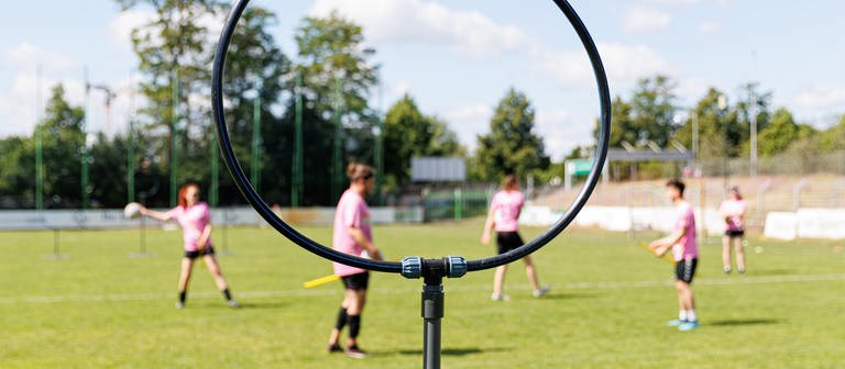 Ein Ständer mit einem Ring, der als Tor dient, steht auf dem Spielfeld. Quidditch ist ein Kontaktsport, der in gemischtgeschlechtlichen Teams gespielt wird und Elemente aus verschiedenen Ballsportarten miteinander vereint. (Foto: dpa Bildfunk, picture alliance/dpa | Michael Matthey)