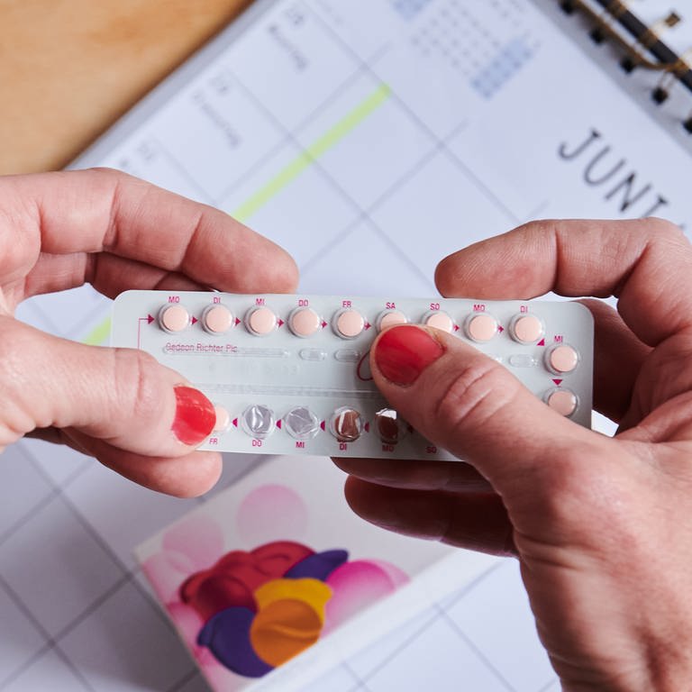 Über einem Kalender nimmt sich eine Frau die nächste Pille aus der Monatspackung der Antibabypille. (Foto: dpa Bildfunk, picture alliance/dpa | Annette Riedl)