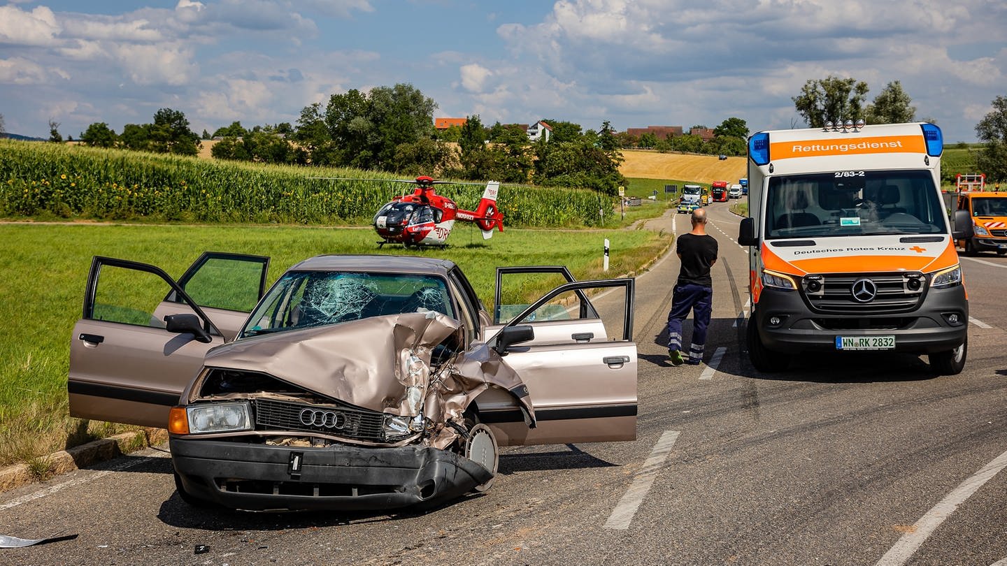 Rettungskräfte sind an einer Unfallstelle neben einem Autowrack und einem Rettungshubschrauber im Einsatz. (Foto: picture-alliance / Reportdienste, picture alliance/dpa/KS-Images.de | Karsten Schmalz)