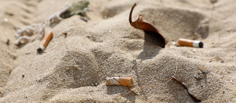 Zigarettenstummel liegen im Sand am Strand von Arenal. Das Rauchen schadet laut Weltgesundheitsorganisation (WHO) nicht nur der Gesundheit, sondern auch der Umwelt enorm. (Foto: dpa Bildfunk, picture alliance/dpa | Clara Margais)