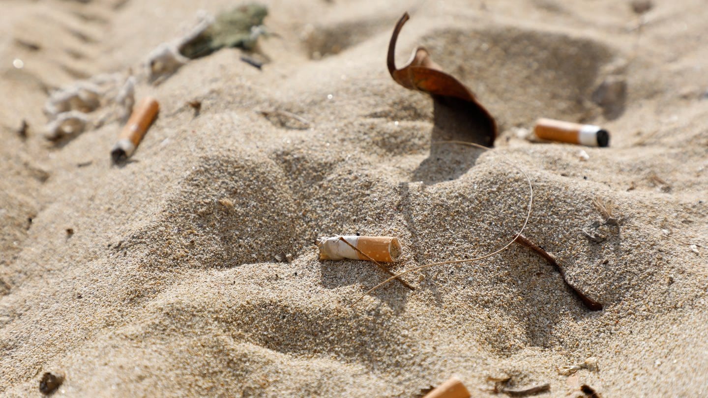 Zigarettenstummel liegen im Sand am Strand von Arenal. Das Rauchen schadet laut Weltgesundheitsorganisation (WHO) nicht nur der Gesundheit, sondern auch der Umwelt enorm.