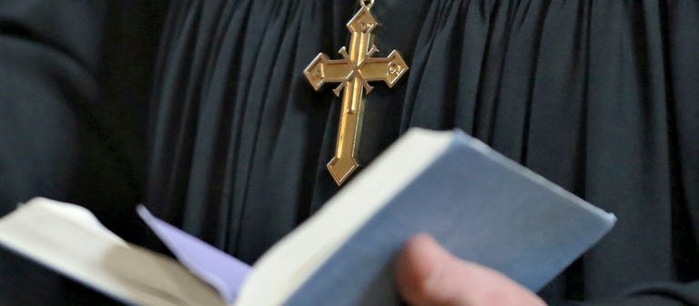 Ein Geistlicher hält beim Gottesdienst eine Bibel in der Hand. (Foto: picture-alliance / Reportdienste, picture alliance/dpa/dpa-Zentralbild | Jan Woitas)