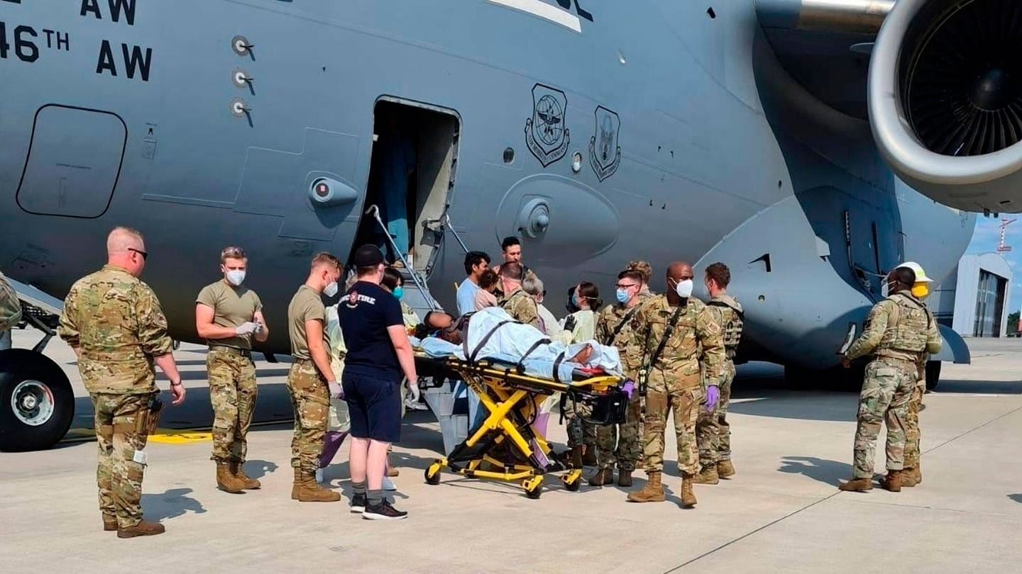 Symbolbild: Medical support personnel from the 86th Medical Group help an Afghan mother and family off a U.S. Air Force C-17, call sign Reach 828, moments after she delivered a child aboard the aircraft upon landing at Ramstein Air Base, Germany (Foto: IMAGO, IMAGO / ZUMA Wire)