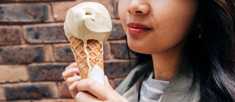 Woman holding melting ice cream in front of wall model released Symbolfoto (Foto: IMAGO, IMAGO / Westend61)