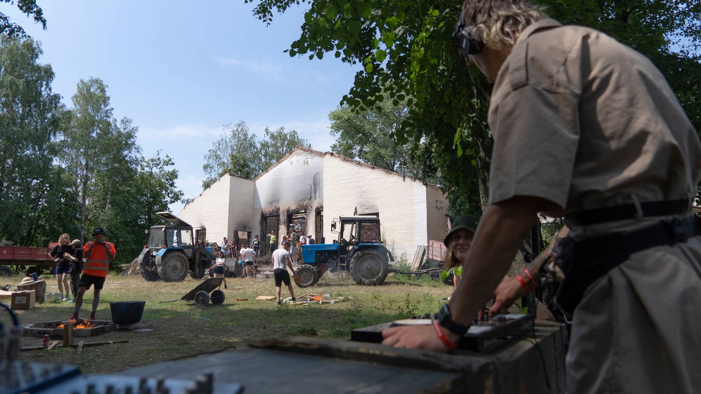 Ein DJ legt Techno-Musik auf, während junge Freiwillige die Trümmer eines durch eine russische Rakete zerstörten Gebäudes im Dorf Jahidne in der Region Tschernihiw beseitigen.