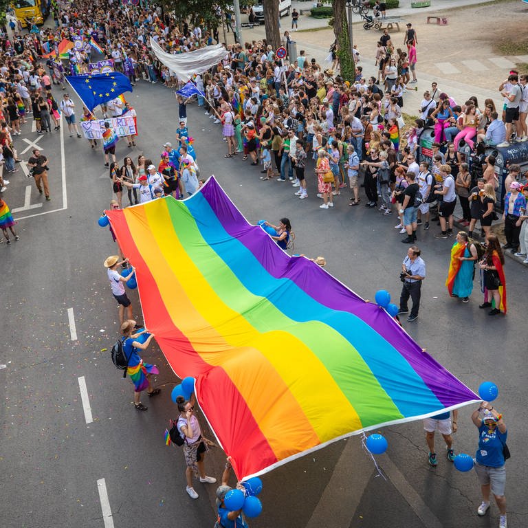 Zahlreiche Menschen tragen eine große Regenbogen-Flagge (Foto: dpa Bildfunk, picture alliance/dpa | Christoph Schmidt)