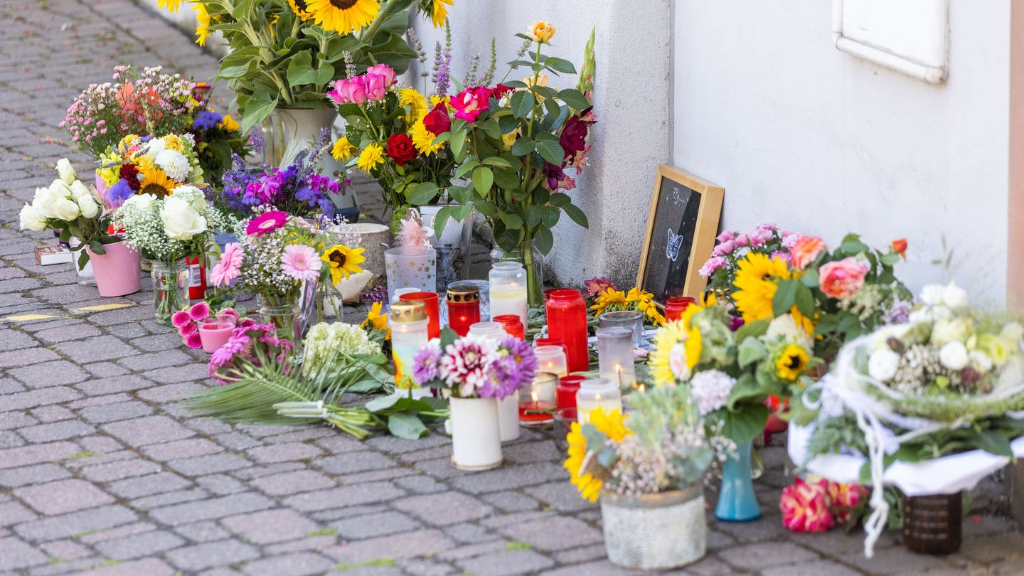 Blumen, Kerzen und Botschaften liegen vor dem Rathaus von Gottenheim, wo Menschen sie in Anteilnahme am Tod einer 14-jährigen abgelegt haben.