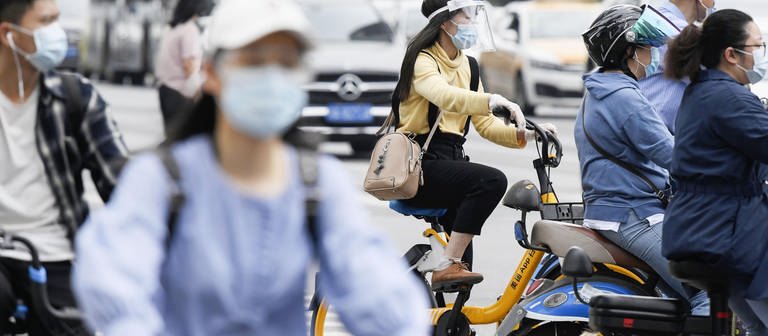 Menschen fahren in Wuhan mit Mundschutzmasken und Gesichtsschutz auf Motorrädern und Fahrrädern zur Arbeit (Foto: dpa Bildfunk, picture alliance/dpa/kyodo | ---)