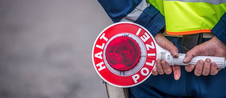 Verkehrskontrolle: Ein Polizist hält eine Kelle in der Hand (Foto: IMAGO, IMAGO / Christian Grube)