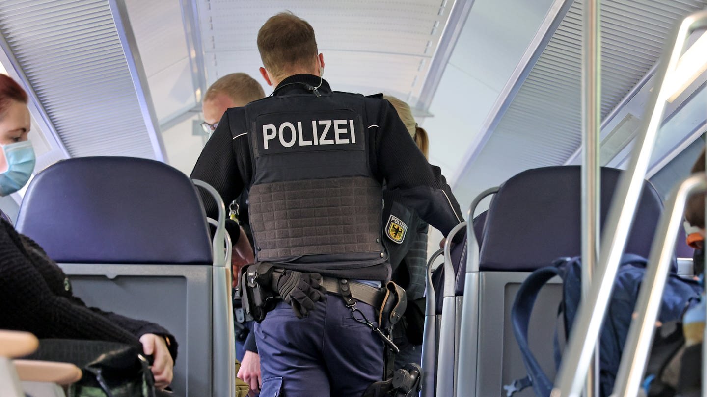 Polizisten der Bundespolizei laufen durch einen Regionalzug der Deutschen Bahn.