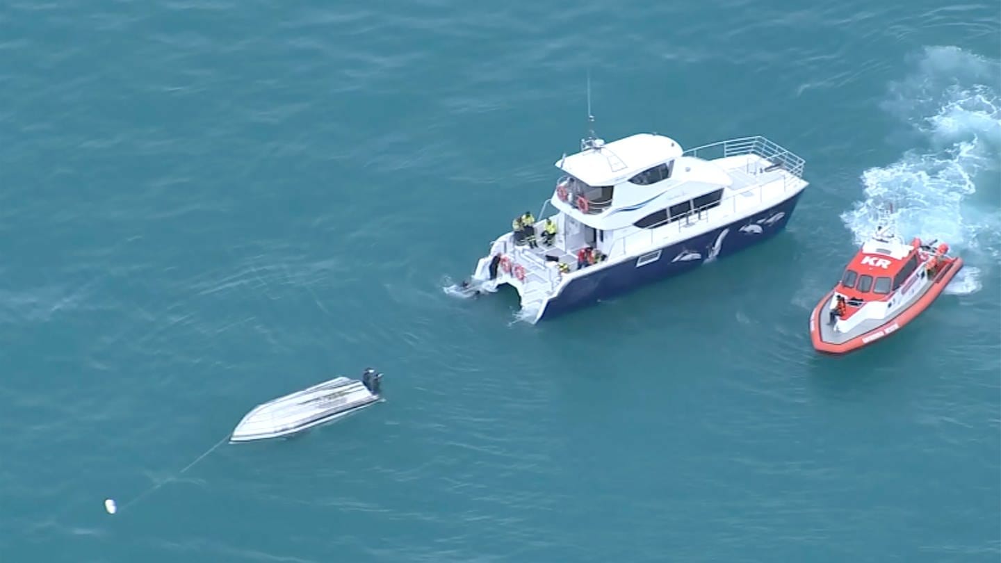 Eine Luftaufnahme eines Videos zeigt zwei Rettungsboote neben einem gekenterten Boot
