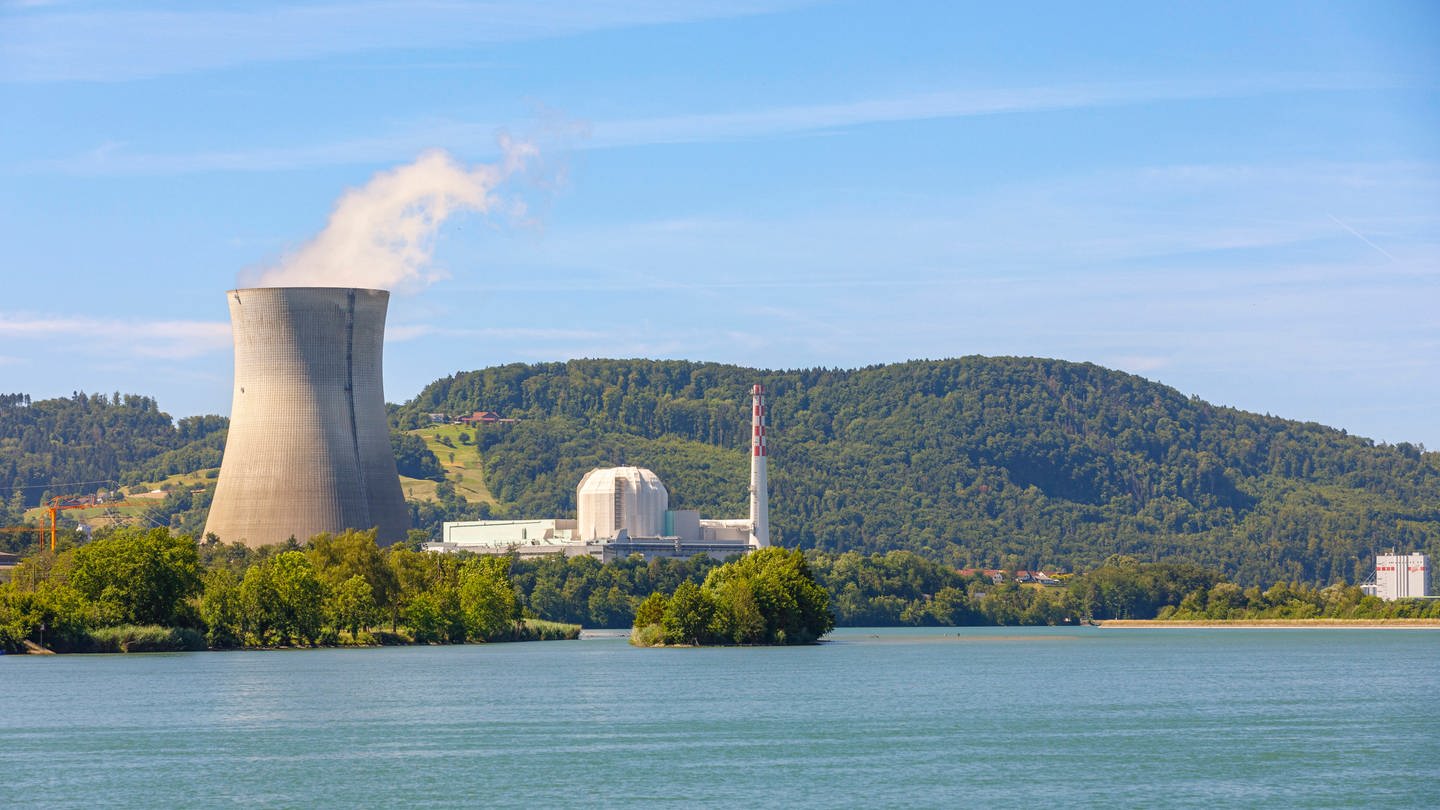 Atomkraftwerk auf der Schweizer Seite des Rheins gegenüber Dogern. Kühlturm links im Bild mit Bergen im Hintergrund und dem Rhein im Vordergrund.