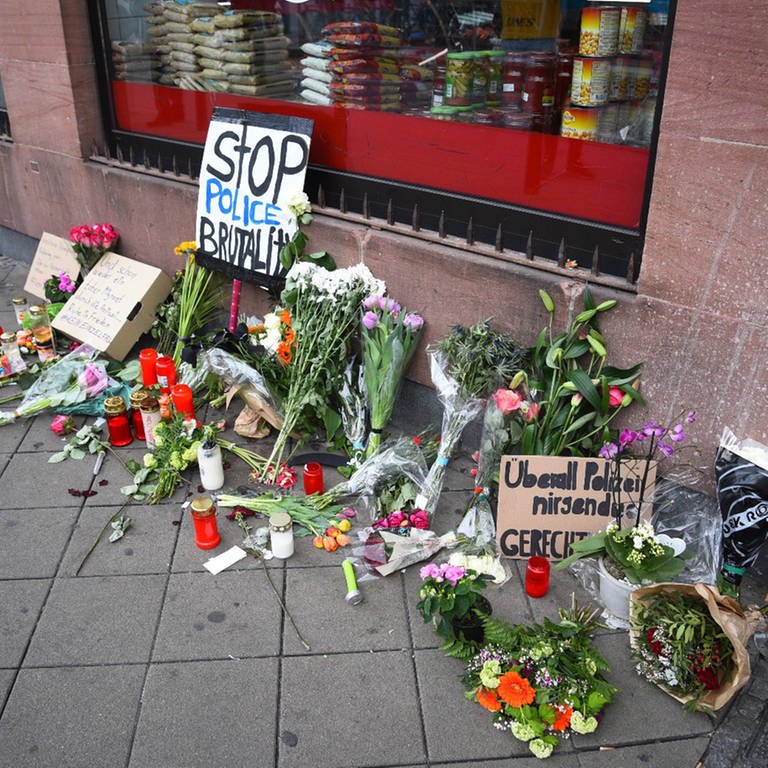 Blumen, Kerzen und Schilder liegen und stehen an dem Ort, an dem am Montag (02.05.2022) ein Mann nach einer Polizeikontrolle gestorben ist. (Foto: picture-alliance / Reportdienste, picture alliance/dpa/PR-Video | René Priebe)