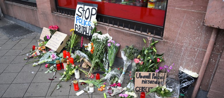 Blumen, Kerzen und Schilder liegen und stehen an dem Ort, an dem am Montag (02.05.2022) ein Mann nach einer Polizeikontrolle gestorben ist. (Foto: picture-alliance / Reportdienste, picture alliance/dpa/PR-Video | René Priebe)
