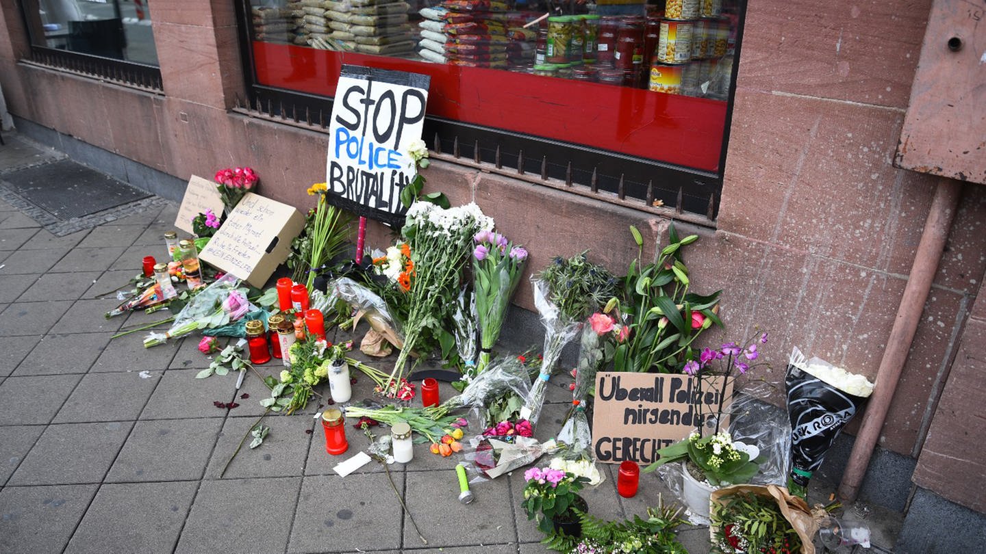 Blumen, Kerzen und Schilder liegen und stehen an dem Ort, an dem am Montag (02.05.2022) ein Mann nach einer Polizeikontrolle gestorben ist.