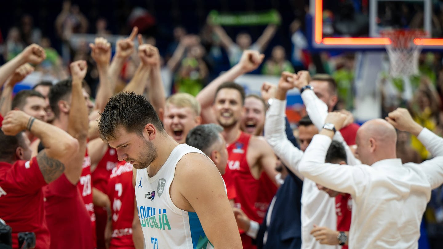 Basketballer Luka Doncic nach dem Spiel gegen Polen bei der EM mit hängendem Kopf. Im Hintergrund feiert die polnische Mannschaft