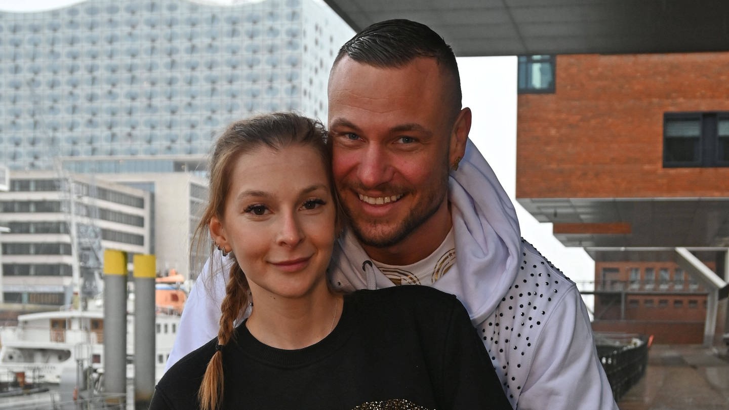 Eric Sindermann und seine Freundin Katharina lächeln im Hamburger Hafen für ein Foto.