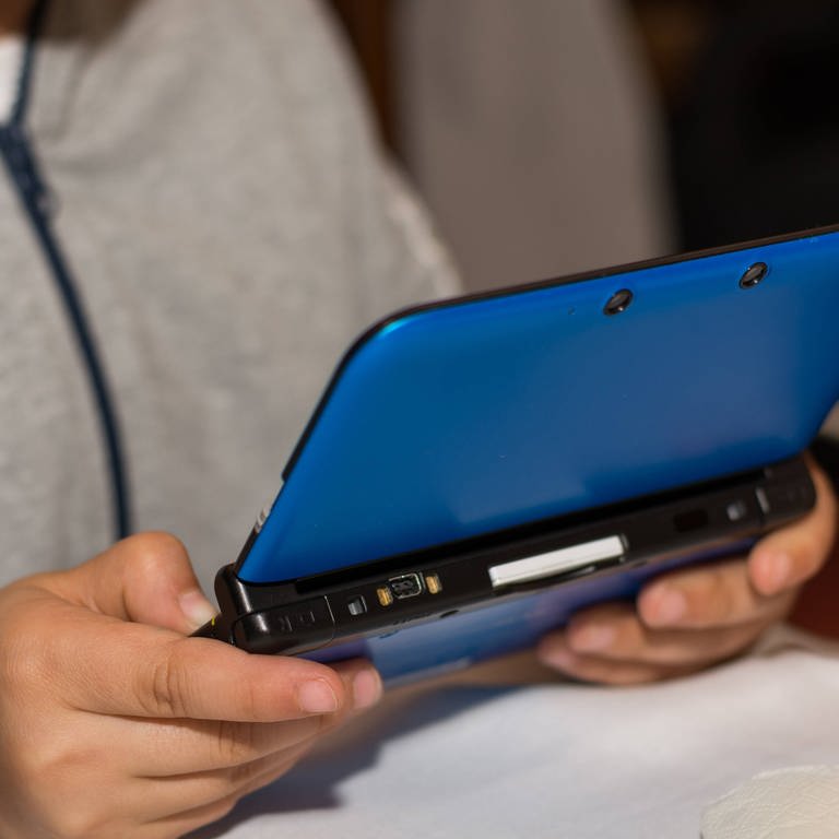 Eine nicht näher zu erkennende tragbare Spielekonsole, auch Handheld genannt, wird von einem Jugendlichen mit beiden Händen gehalten. (Foto: IMAGO, IMAGO / CHROMORANGE)