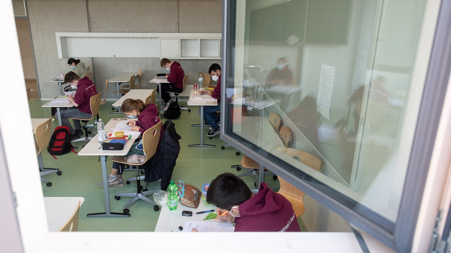 Schülerinnen und Schüler mit medizinischen Masken lesen sich am ersten Tag der Abiturprüfungen bei offenem Fenster in einem Klassenzimmer die Prüfungsaufgaben durch. (Foto: dpa Bildfunk, picture alliance/dpa | Sebastian Gollnow)