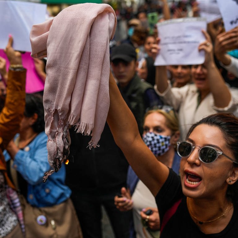 Eine Frau hält ein Kopftuch hoch, während sie mit anderen Demonstrierenden bei einem Protest gegen den Tod der Iranerin Mahsa Amini vor dem iranischen Generalkonsulat Parolen ruft. (Foto: dpa Bildfunk, picture alliance/dpa/AP | Francisco Seco)