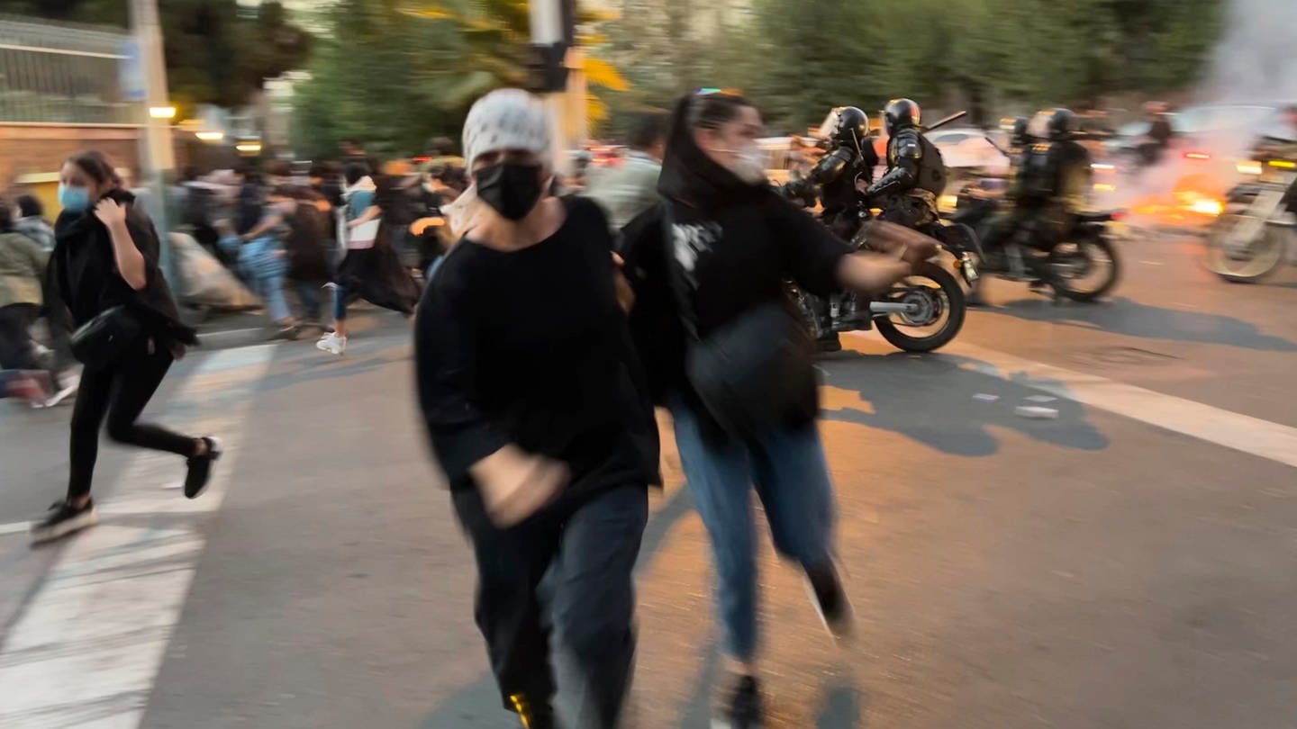 Frauen im Iran fliehen vor der Polizei als sie auf der Straße demonstrieren.