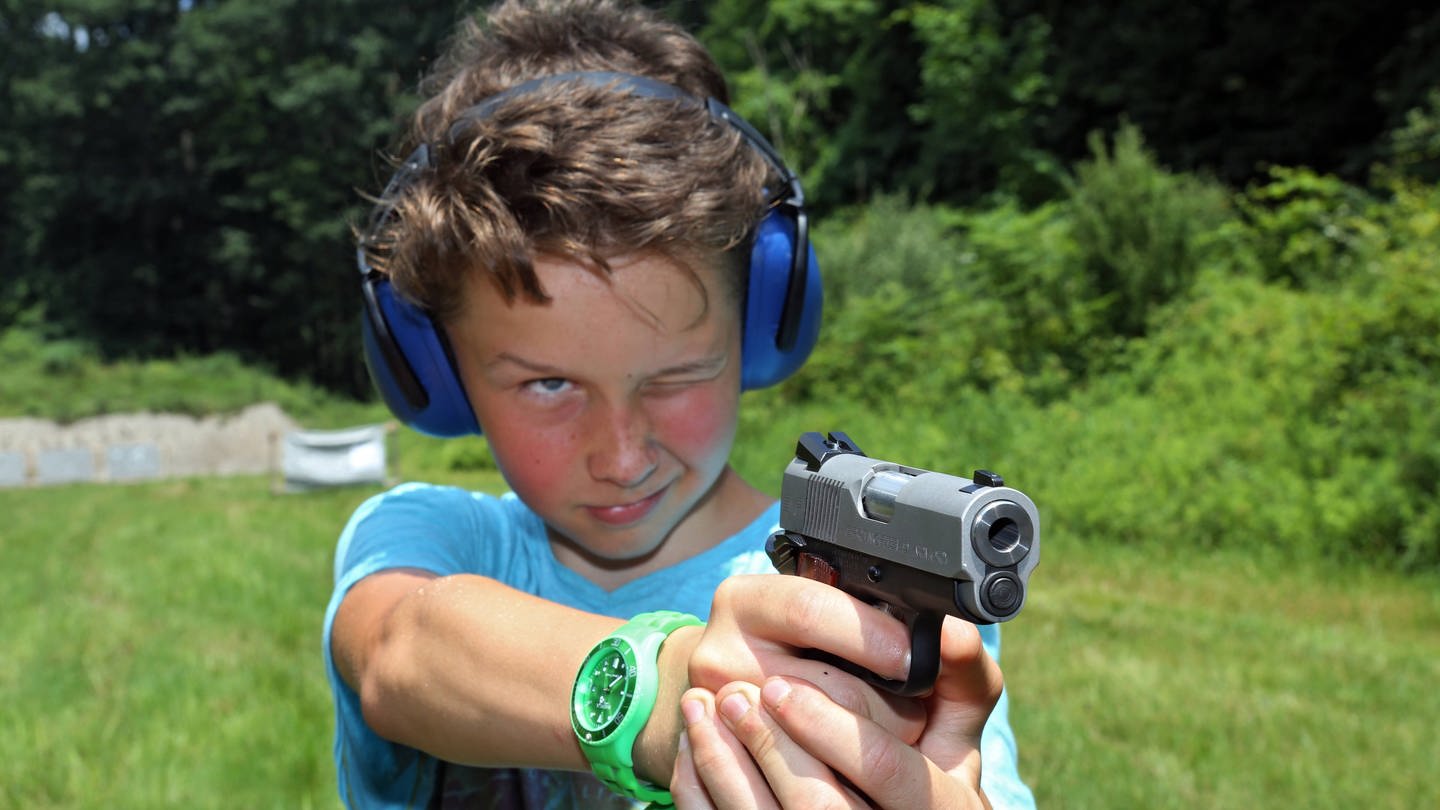 Junge zielt mit einer Pistole.