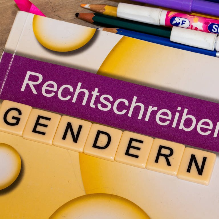 Symbolbild Gendern: Buchstabenwürfel auf einem Grundschulbuch zeigen das Wort Gendern. (Foto: IMAGO, IMAGO / U. J. Alexander)