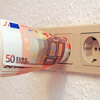 Geld in Steckdose (Foto: IMAGO, IMAGO / McPHOTO)