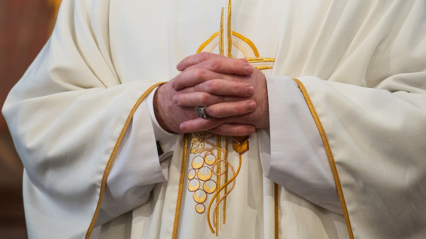 Symbolbild; Ein Priester trägt sein Gewand und faltet seine Hände.