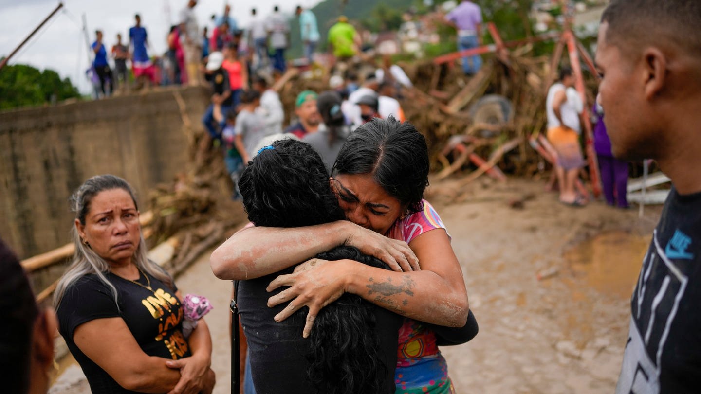 Anwohner umarmen sich nach einem durch heftigen Regen verursachten Erdrutsch. (Foto: dpa Bildfunk, picture alliance/dpa/AP | Matias Delacroix)