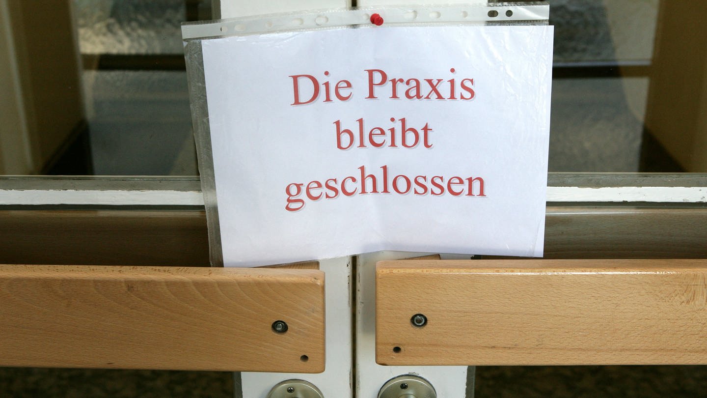An einer Tür zu einer Arztpraxis hängt ein Schild mit der Aufschrift «Die Praxis bleibt geschlossen». (Foto: dpa Bildfunk, picture alliance / dpa | Patrick Pleul)