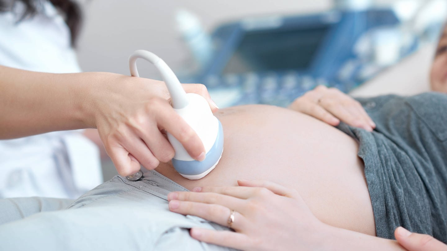 Doctor using ultrasound equipment screening of pregnant woman.