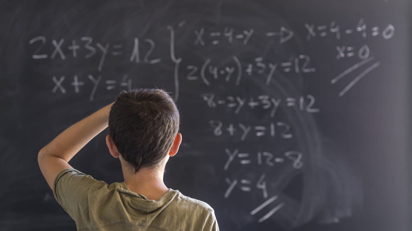 Kind löst eine Gleichung an einer Tafel (Foto: IMAGO, IMAGO / agefotostock)