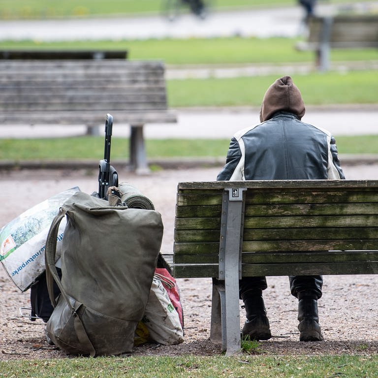 Ein Mann sitzt mit seinen Habseligkeiten auf einer Parkbank. (Foto: dpa Bildfunk, picture alliance/dpa | Sebastian Gollnow)