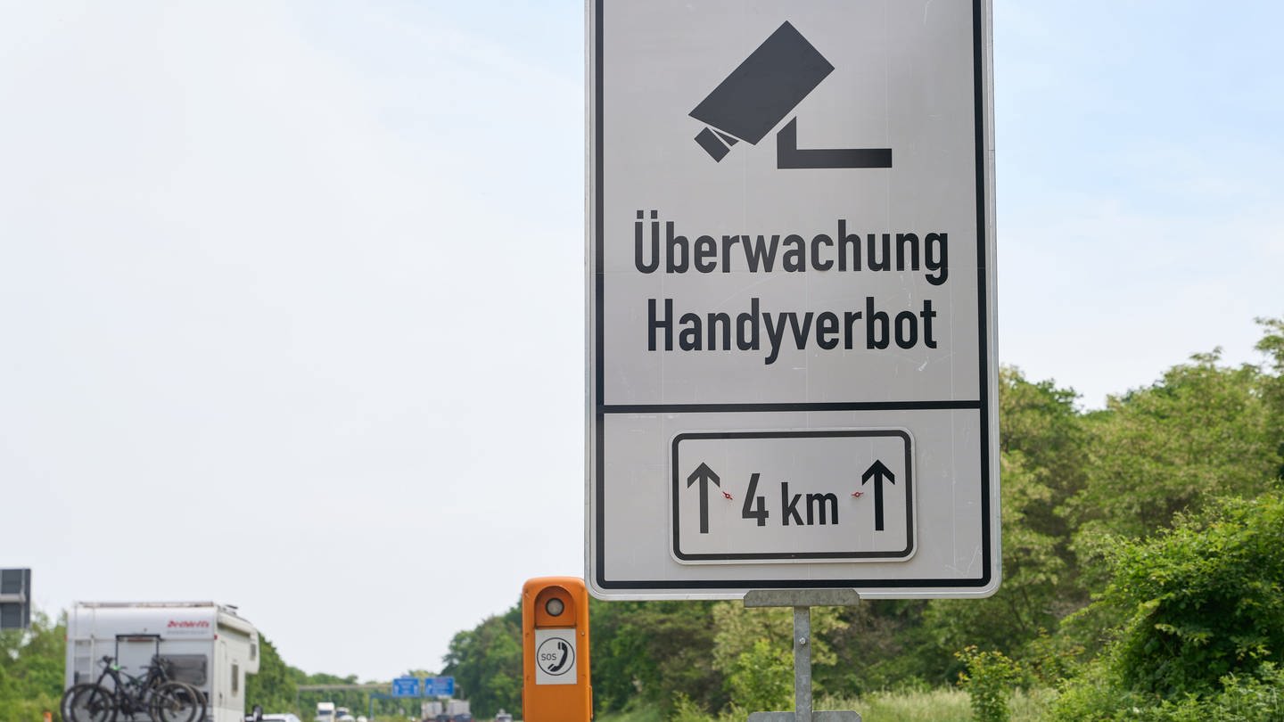 Ein Schild an der Autobahn A60 weist auf den Einsatz eines neuartigen Systems zur Feststellung von Handyverstößen am Steuer hin.