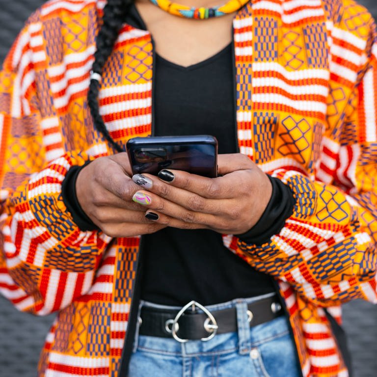 Eine junge Frau hält ein Smartphone in den Händen. (Foto: IMAGO, IMAGO / Addictive Stock)