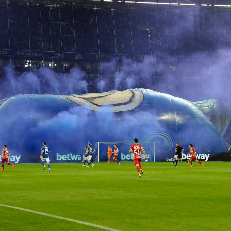 Das Trikot Banner, gefüllt mit blauem Pyro-Rauch, sinkt in sich zusammen. (Foto: IMAGO, IMAGO / Kolvenbach)
