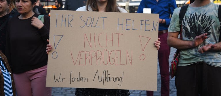 Frau hält Schild gegen Polizeigewalt hoch (Foto: dpa Bildfunk, picture alliance/dpa/PR-Video | René Priebe)