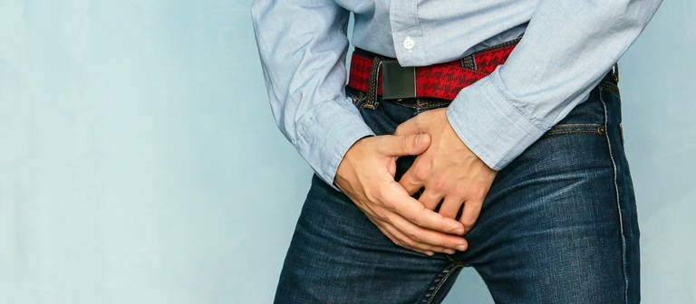 Symbolbild Hodenkrebs: Ein Mann in Jeans hält sich den Schritt. (Foto: IMAGO, agefotostock)