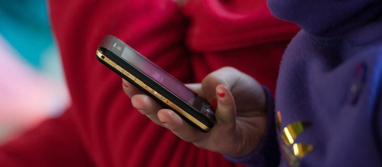 Eine Schülerin hält ein mobiles Telefon in der Hand. Bei Kinderporngrafie ermittelt die Polizei immer öfter auch gegen Minderjährige. (Foto: dpa Bildfunk, picture alliance/dpa | Armin Weigel)