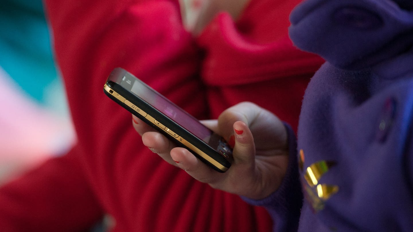 Eine Schülerin hält ein mobiles Telefon in der Hand. Bei Kinderporngrafie ermittelt die Polizei immer öfter auch gegen Minderjährige.