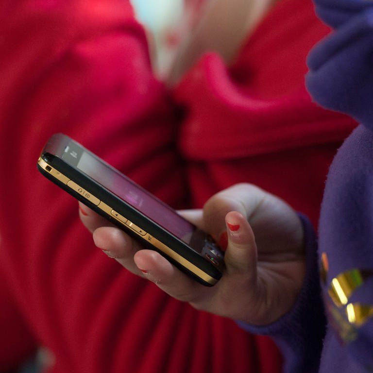 Eine Schülerin hält ein mobiles Telefon in der Hand. Bei Kinderporngrafie ermittelt die Polizei immer öfter auch gegen Minderjährige. (Foto: dpa Bildfunk, picture alliance/dpa | Armin Weigel)