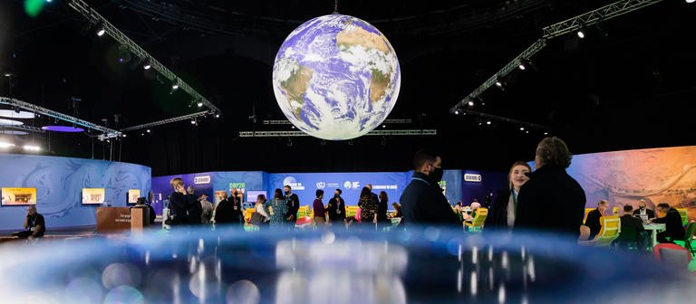 Teilnehmende des Klimagipfels COP26 unter einer beleuchteten Weltkugel (Symbolbild) (Foto: dpa Bildfunk, picture alliance/dpa | Christoph Soeder)