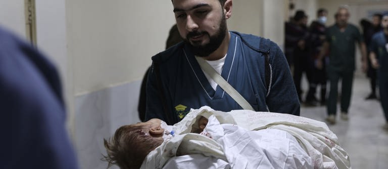 Medizinisches Personal trägt ein verletztes Kind nach einem Angriff. Im Norden Syriens sind mehrere Menschen bei Bombardierungen getötet worden. (Foto: picture-alliance / Reportdienste, picture alliance/dpa | Anas Alkharboutli)