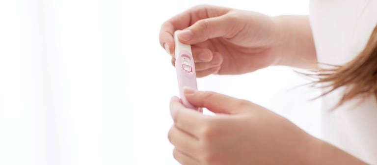 Eine Frau hält einen Schwangerschaftstest in den Händen. (Foto: IMAGO, IMAGO / AFLO)