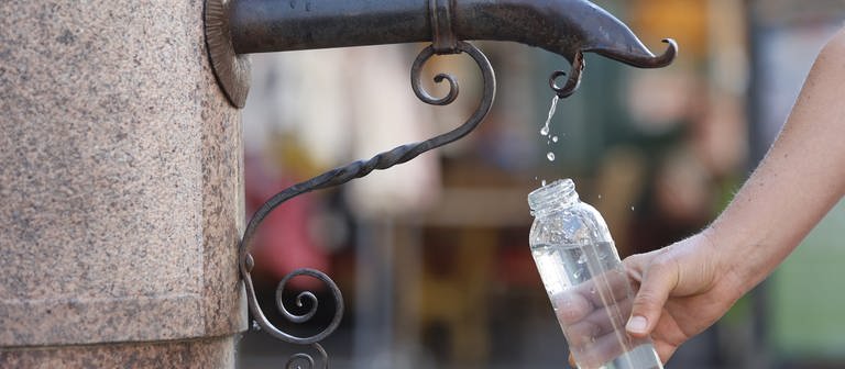 Eine Frau bedient sich am Trinkwasserspender im Stadtzentrum. (Foto: dpa Bildfunk, picture alliance/dpa | Matthias Bein)