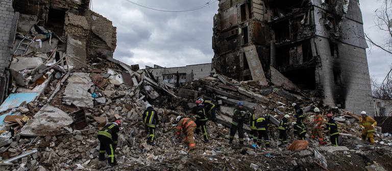Symbolbild Russland-Ukraine-Krieg: Ukrainische Feuerwehrleute suchen nach Überlebenden unter den Trümmern eines zerstörten Wohnhauses in Borodyanka (Foto: DASDING, picture alliance/dpa/SOPA Images via ZUMA Press Wire | Alex Chan)